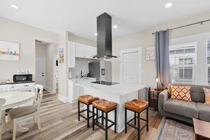 A modern kitchen with a central island, white cabinetry, and a stainless steel range hood.