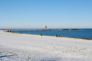 A beach with a lighthouse in the distance, a clear sky, and a calm sea. - Mühlentrift 32, Apt. 6 (Cuxhaven)