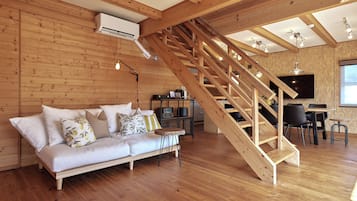 A wooden interior with a sofa, a staircase, and a flat-screen TV.