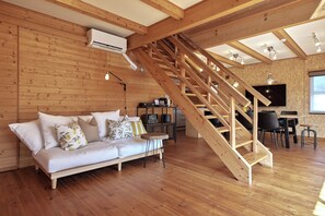 Interior em madeira com sofá, escada e televisão de tela plana.