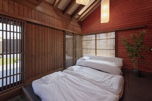 Una habitación con cama, paredes de madera y una ventana con persianas verticales.