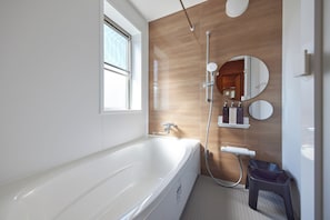 Un baño moderno con bañera, ducha y tocador con espejo.