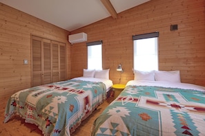 Habitación con dos camas, paredes de madera, un ventanal y un equipo de aire acondicionado.