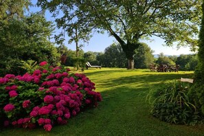 A well-maintained garden with a lawn, a large tree, and a seating area with chairs. - at the Haslinger holiday farm (Winzer)