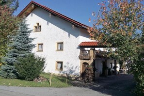 A two-story building with a red-tiled roof, a stone entrance, and a small balcony. - at the Haslinger holiday farm (Winzer)
