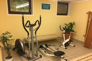 Un espace dédié à la remise en forme, équipé d’appareils d’exercice, d’un banc et d’une plante en pot.