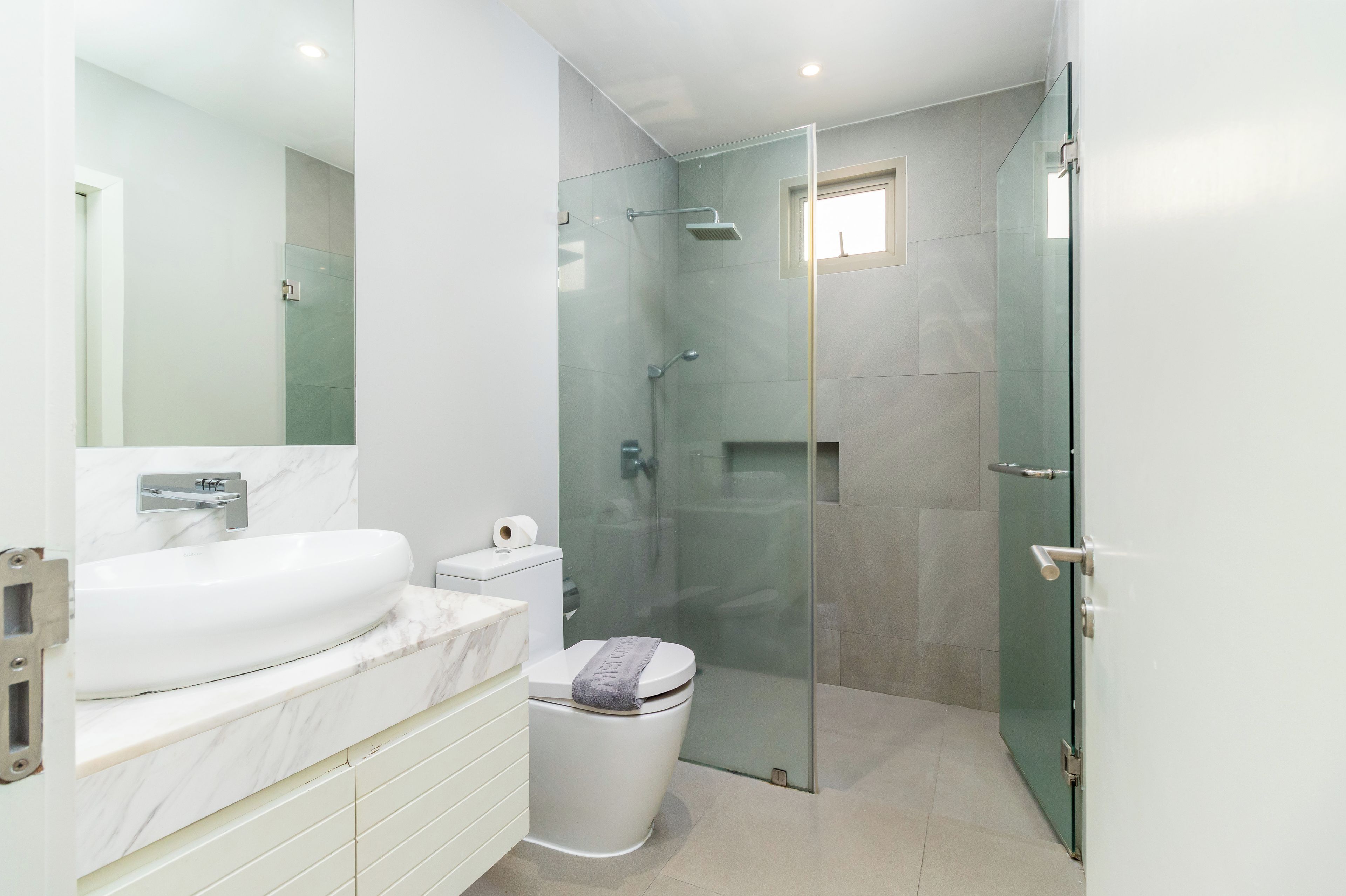 A modern bathroom with a glass-enclosed shower, a white sink, and a toilet.