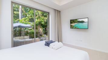 Un dormitorio con una ventana grande, una cama, un televisor en la pared y vistas a la playa.