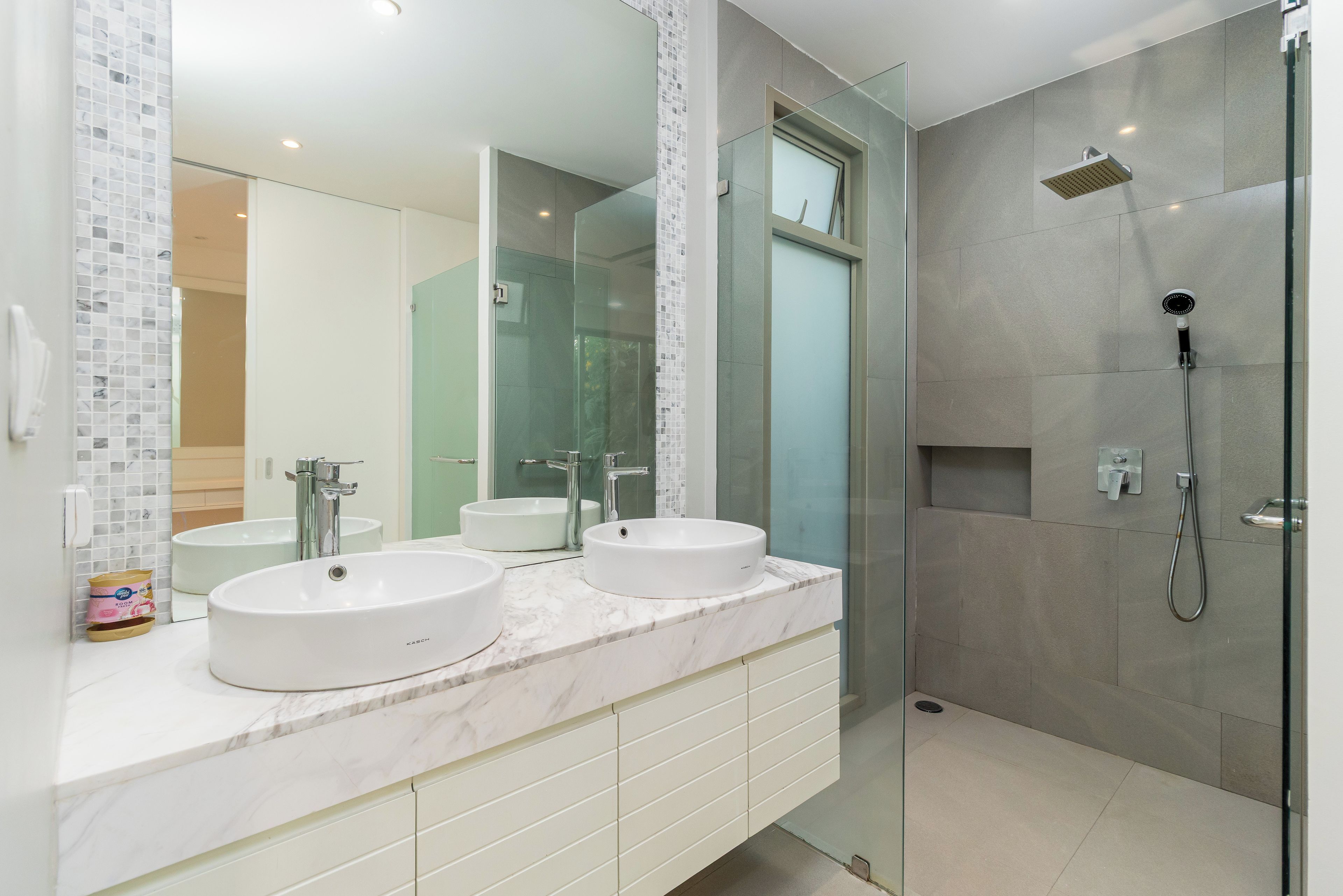 Un baño moderno con dos lavamanos, una cabina de ducha de vidrio y un espejo grande.