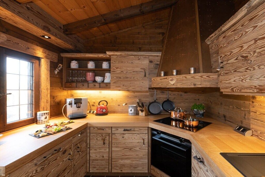 Eine Küche mit Holzschränken, einem eingebauten Backofen und einem Fenster mit Tageslicht.