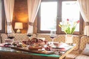 A dining table set with various food items and drinks, a vase with flowers, and a sofa in the background. - Cabin in Kopp with swimming pool (Kopp)