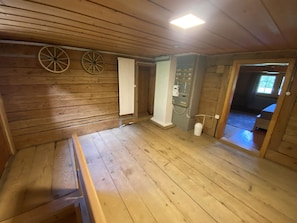 Un interno in legno con una panca, una porta che dà su un'altra stanza e un quadro elettrico a parete.