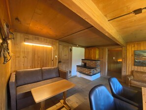 Un interno in legno con un divano, un tavolo, sedie, un caminetto e una porta che dà su un'altra stanza.