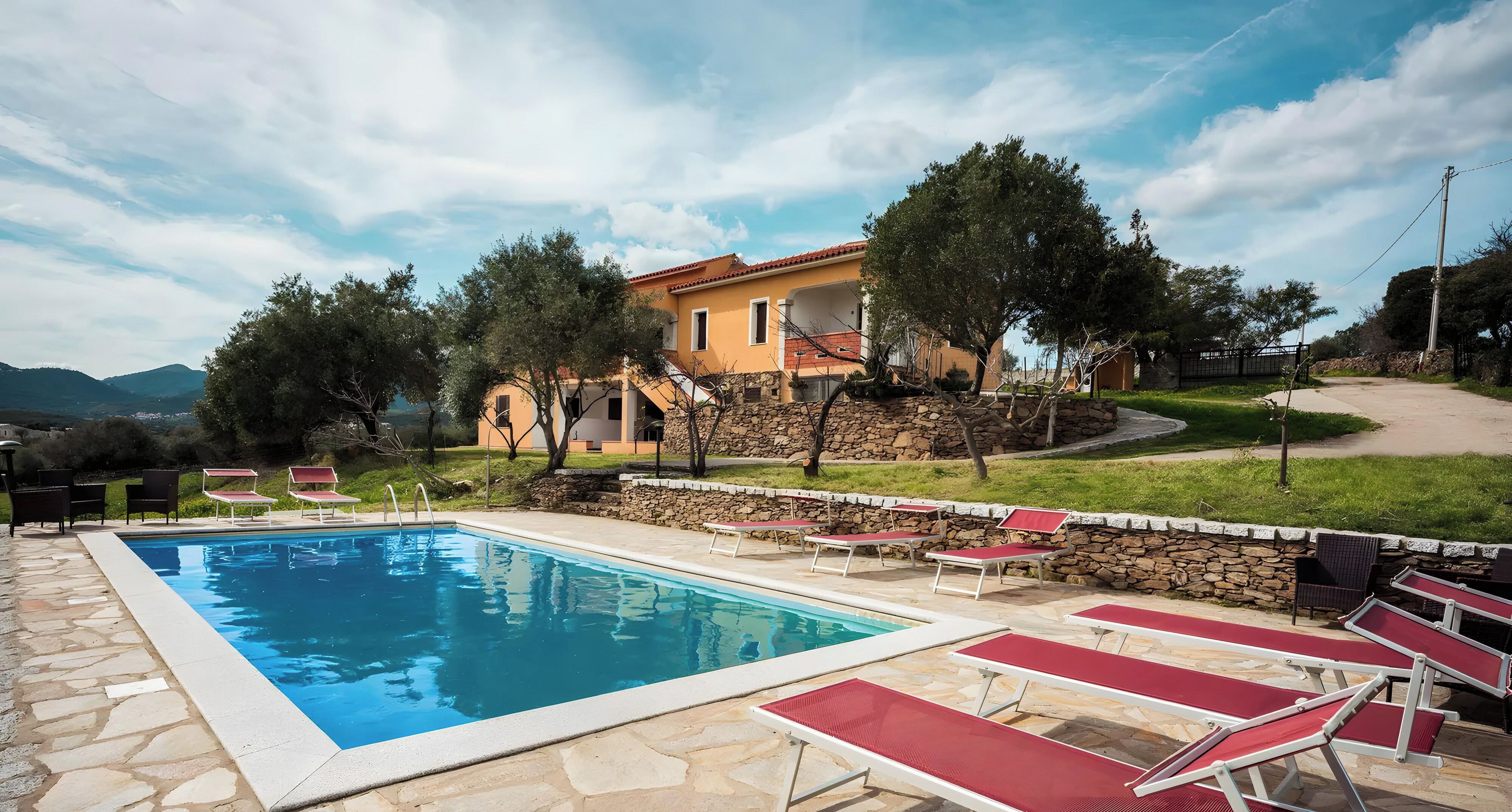 A swimming pool with lounge chairs and a stone wall.