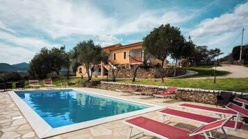 A swimming pool with lounge chairs and a stone wall.