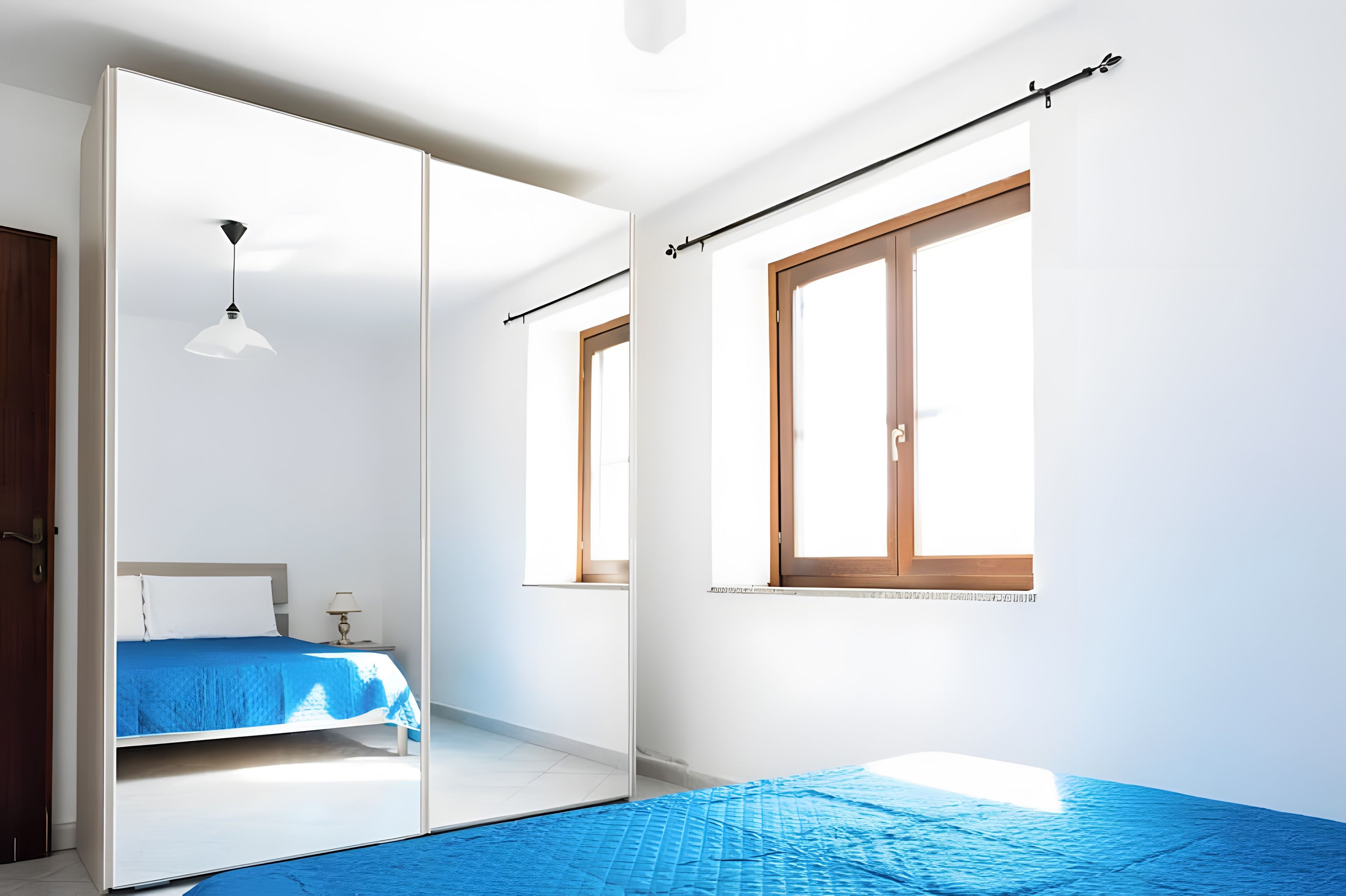 Un dormitorio con cama, mesita de noche, lámpara, ventana y puerta corredera.