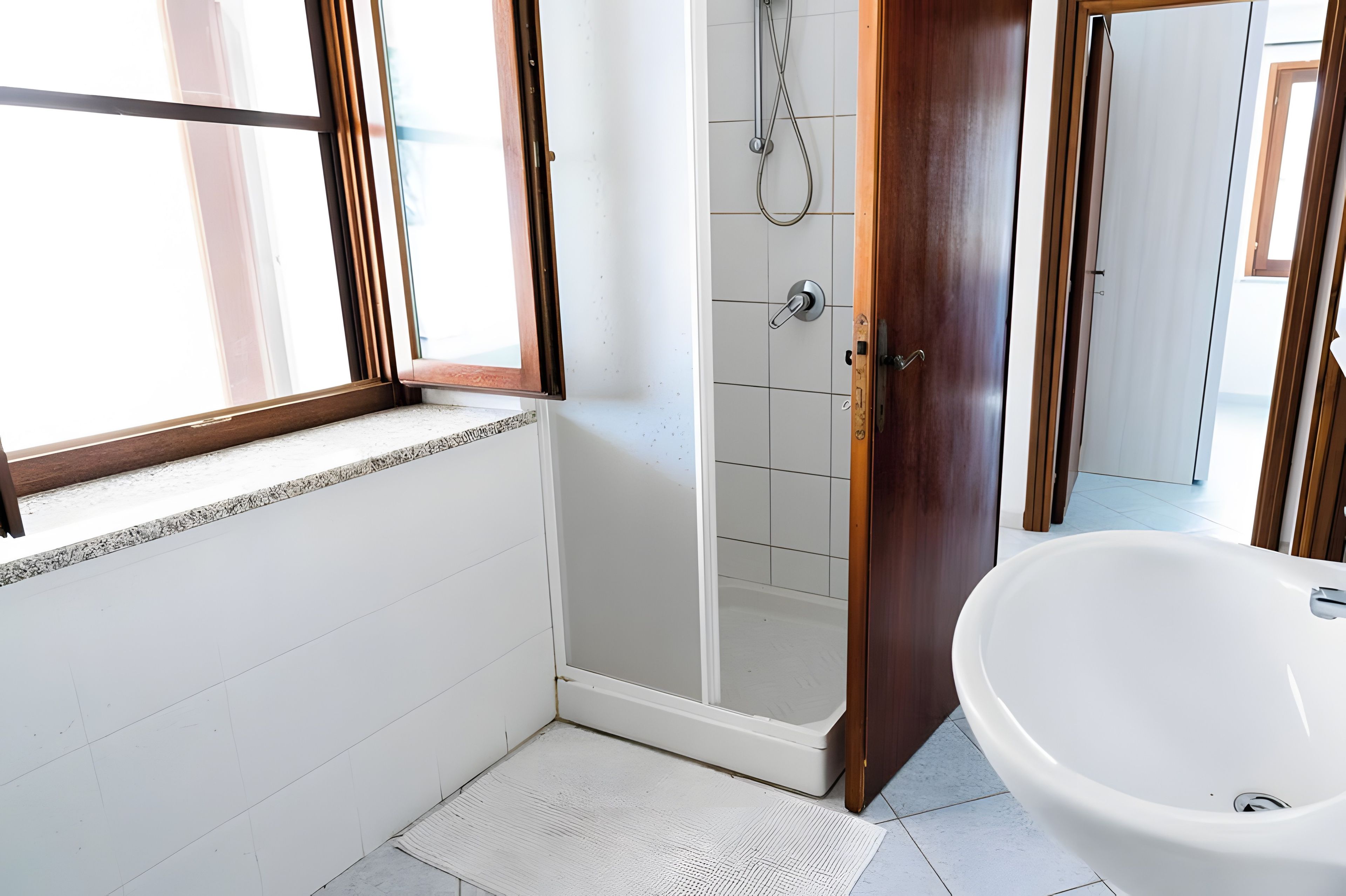 A bathroom with a shower, a sink, and a window.