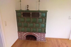 A room with a fireplace, a wooden floor, and a white wall. - Holiday home with 4 bedrooms (Altusried)