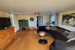 A living room with a television, a glass coffee table, a sofa, and a fireplace. - Holiday home with 4 bedrooms (Altusried)
