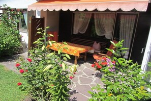 A patio area with a table and chairs, surrounded by potted plants and flowers. - Wank in the house of Georg (Garmisch-Partenkirchen)