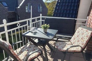 An outdoor balcony with a table, chairs, and a potted plant. - Holiday apartment with 2 bedrooms (Wangerland)