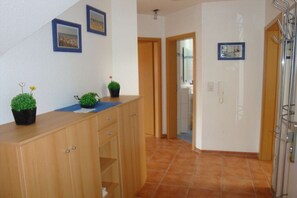 A hallway with a wooden cabinet, potted plants, and framed pictures on the wall. - Holiday apartment with 2 bedrooms (Wangerland)