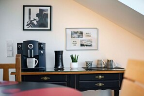Habitació moderna amb màquina de cafè, un quadre emmarcat i escriptori amb calaixos.