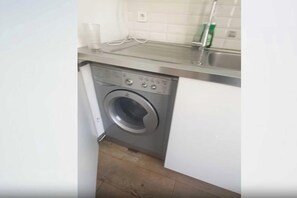 A compact kitchen with a built-in washing machine, a countertop, and a sink. - Charming Apartment 1BR/4P - Le Marais (Paris)