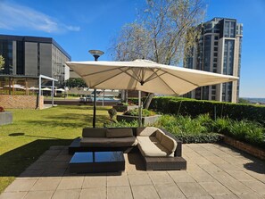 Ein Außenbereich mit Sitzgelegenheit, einem großen Sonnenschirm, einer Couch und einem Couchtisch.