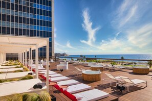 A rooftop lounge with sun loungers, a pool area, and a view of the ocean. - Brut Seafront Hotel By Sunday-Deluxe Family Room for 4 (Tel Aviv)