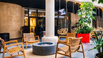 A modern outdoor seating area with wooden chairs and a central fire pit.