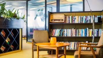 A modern reading area with a bookshelf, two chairs, a small table, and a lamp.