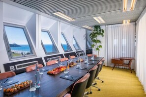 Ein Konferenzraum mit einem langen Tisch, Stühlen und Meerblick durch Oberlichter.