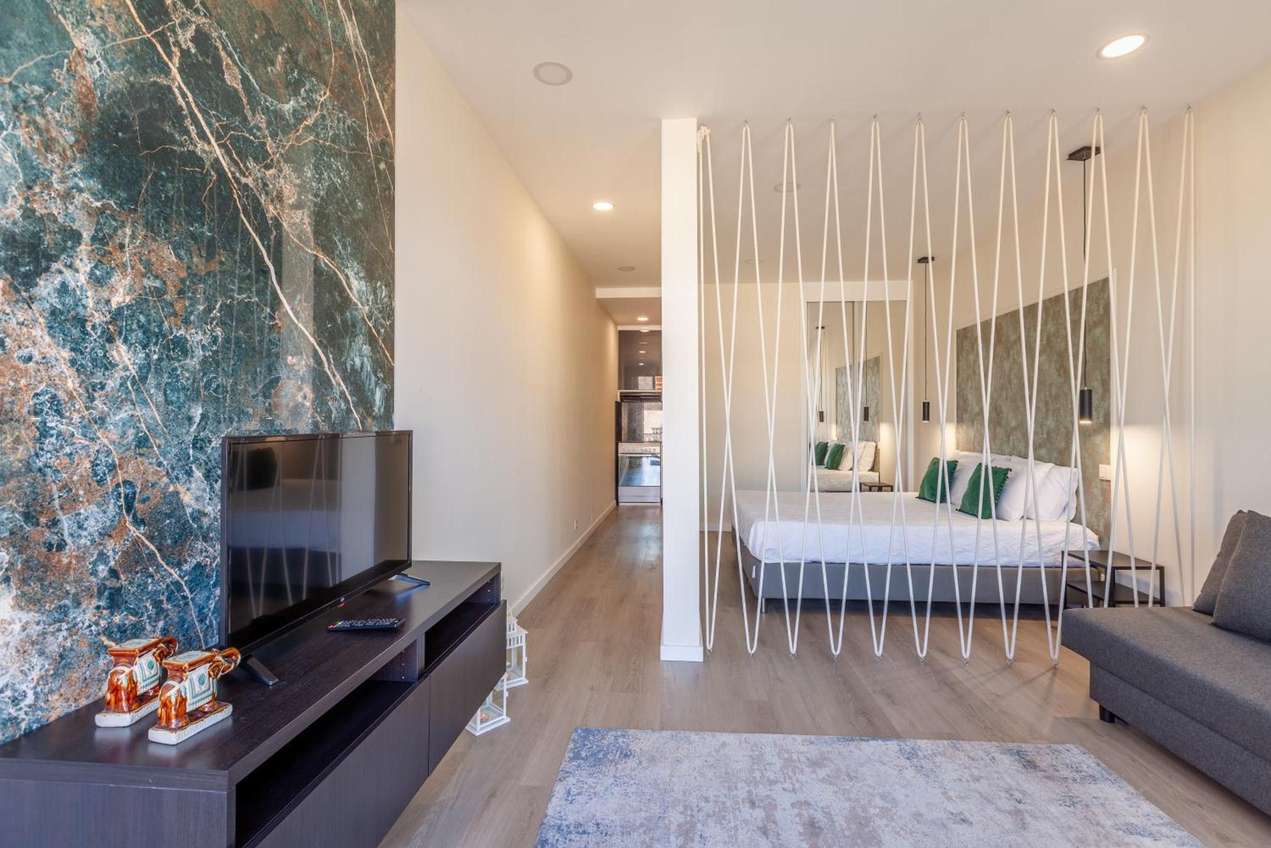 Un dormitorio moderno con cama, televisión y un detalle decorativo en la pared.