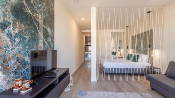 Un dormitorio moderno con cama, televisión y un detalle decorativo en la pared.