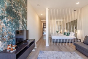 Un dormitorio moderno con cama, televisión y un detalle decorativo en la pared.