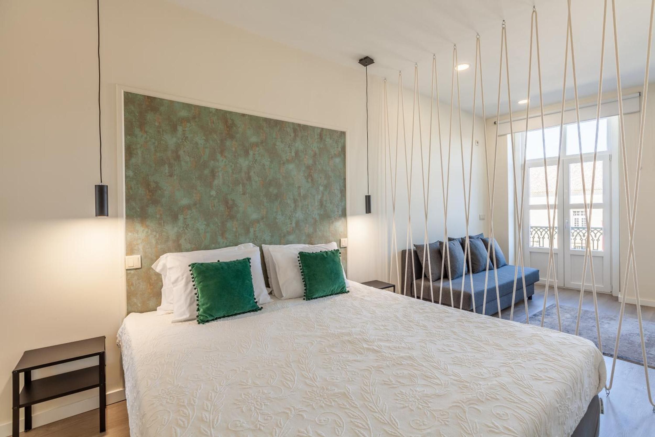 Een slaapkamer met een groot bed, een bank en uitzicht op het omliggende landschap.