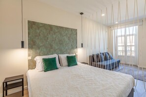 Ein Schlafzimmer mit einem großen Bett, einer Schlafcouch und Blick ins Freie.