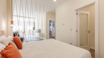 A hotel room with a bed, a desk, and a view of the kitchen and dining area.
