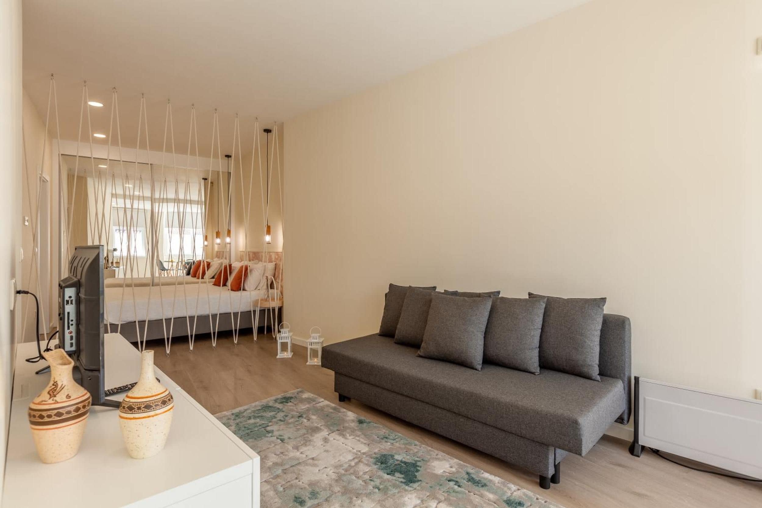 Una sala moderna con un sofá gris, una mesita blanca y un tapete decorativo.