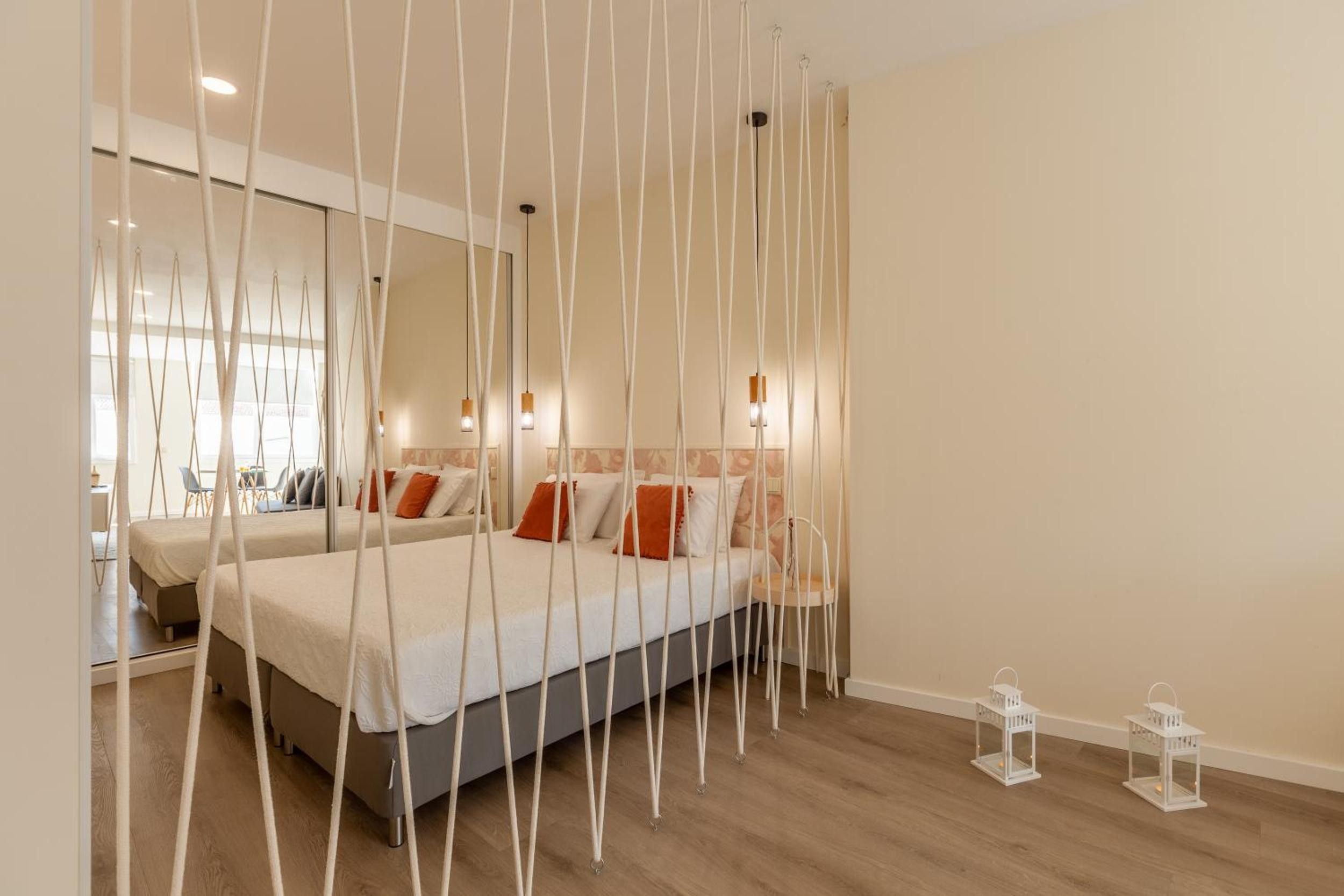 Un dormitorio con cama, espejo y lámpara colgante.