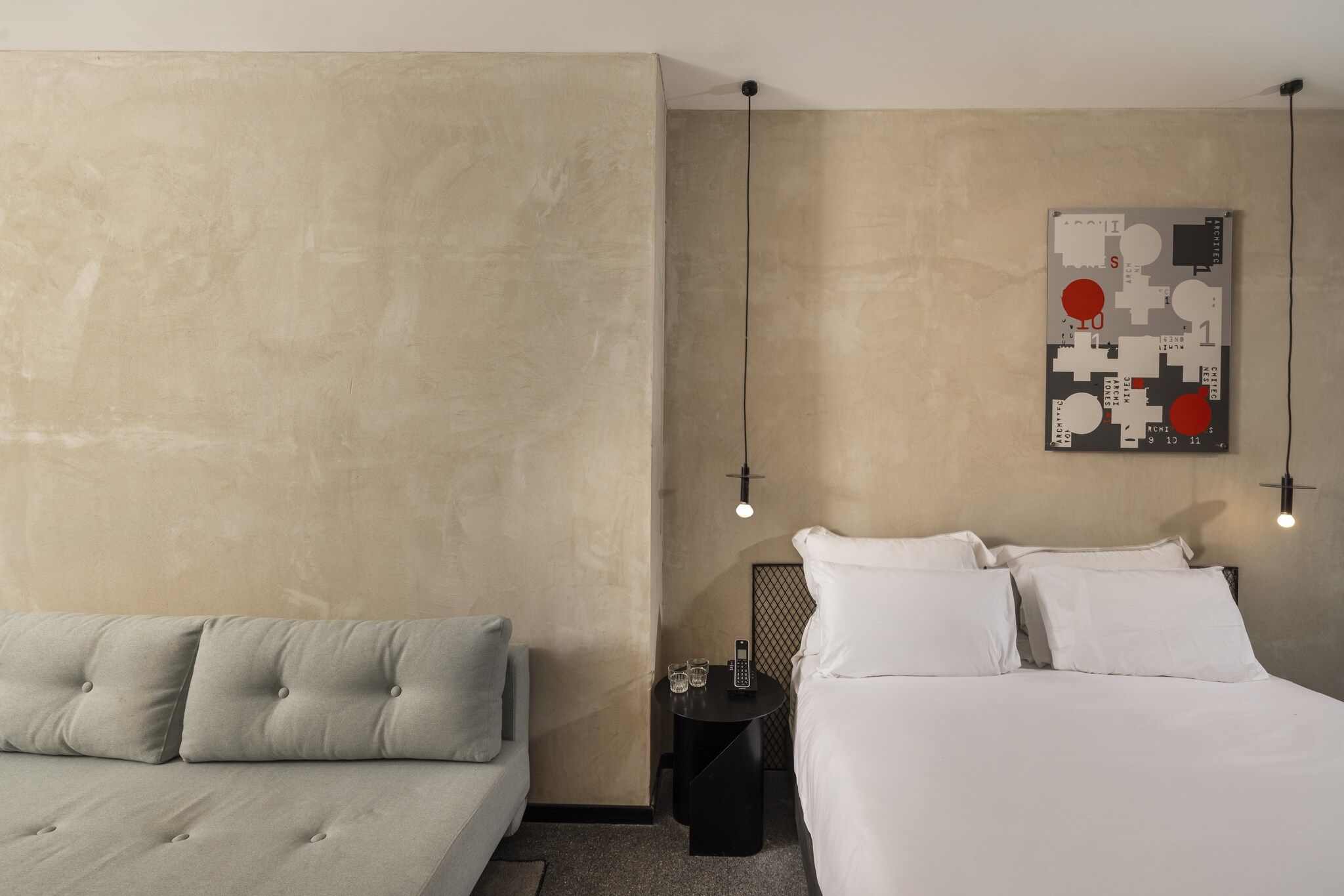 Quarto com cama, mesa de cabeceira e uma obra de arte na parede.