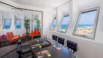 A conference room with a large table, six chairs, and a view of the ocean through skylights.