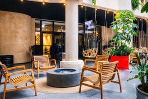 Un área de estar al aire libre, moderna, con sillas de madera y una chimenea central.