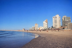Ein Strand mit einer Reihe hoher Gebäude im Hintergrund.