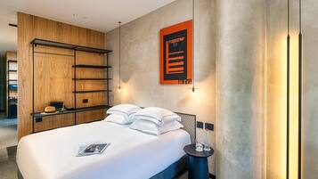 Una habitación de hotel moderna con cama, un armario de madera, estante en la pared y un póster.