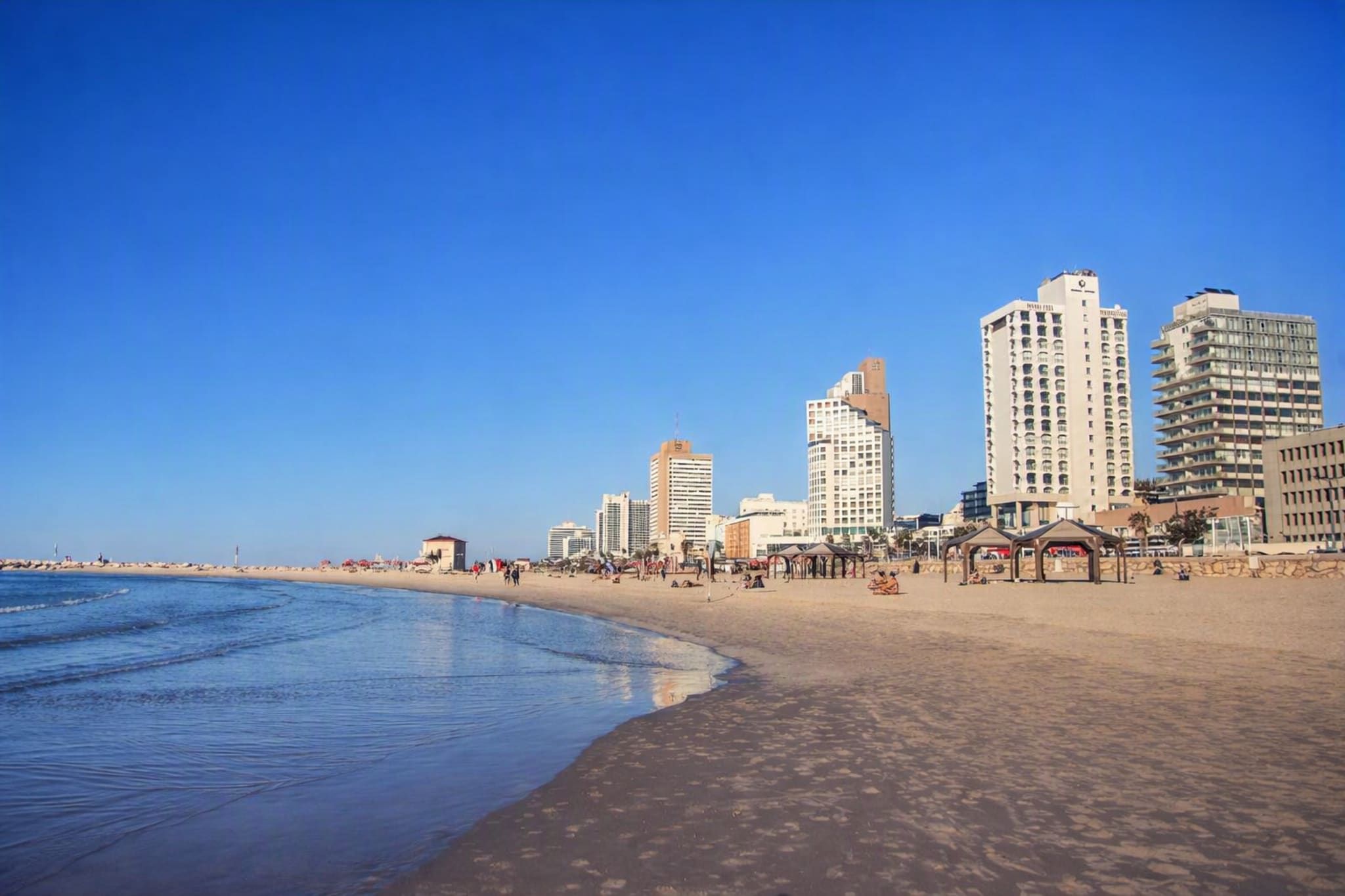 A beach with a row of high-rise buildings in the background.