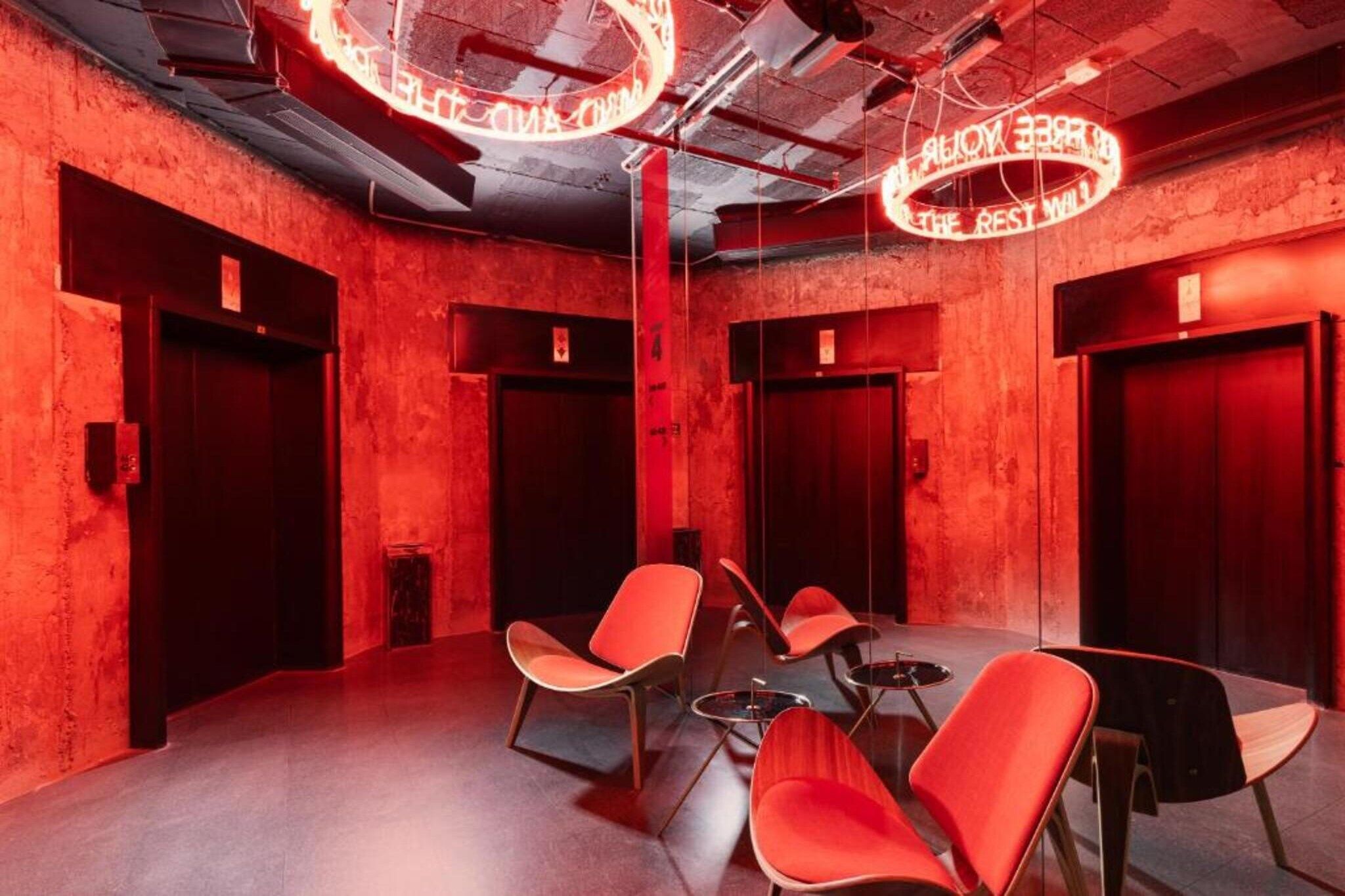 Une salle de conférence aux murs rouges, avec une table ronde et quatre chaises rouges.