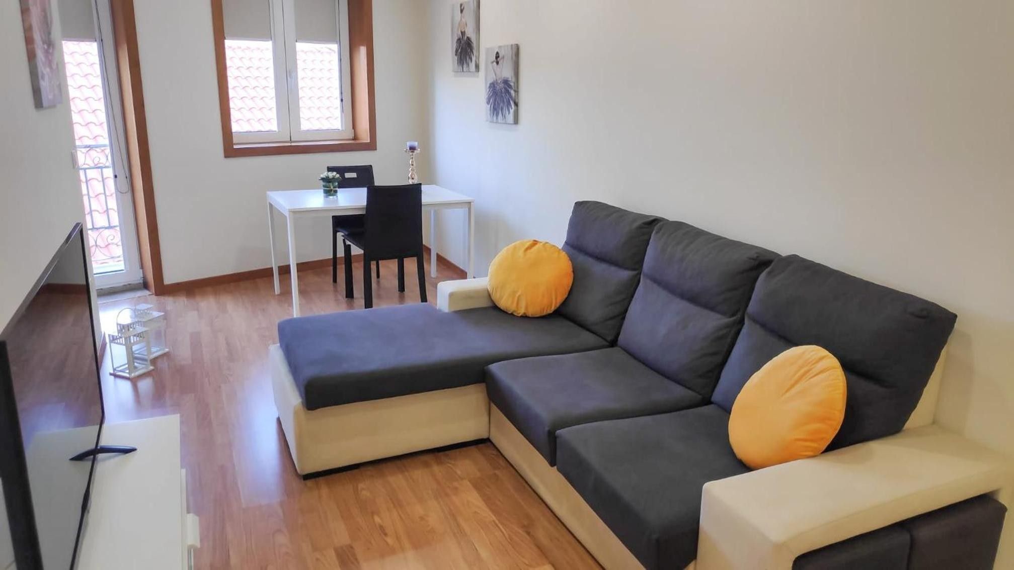 A modern living room with a sectional sofa, a dining table, and a small office desk.