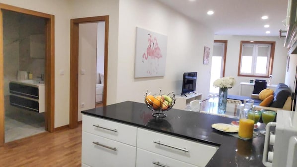 A modern kitchen with a black countertop, white cabinets, and a fruit bowl.